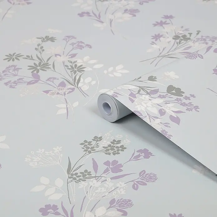 Laura Ashley Vliestapete Igerna Wiesenkerbel - Blau, Floral, 1.000 x 52 cm - Hellblaue Tapete mit zartem Blumenmuster in Violett, Grau und Weiß, teilweise abgerollt zur Ansicht des Designs.