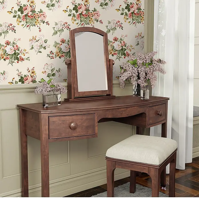 Laura Ashley Vliestapete Rosemore - Mehrfarbig, Floral, 1.000 x 52 cm - Ein Schminktisch aus dunklem Holz mit Spiegel und passendem Polsterhocker in einem Blumenraum.
