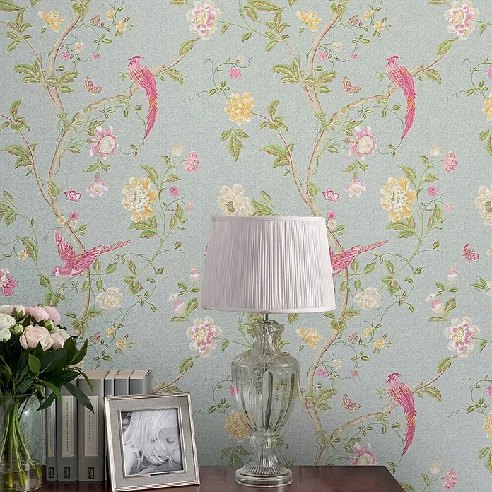 Laura Ashley Vliestapete Vliestapete Sommerpalast - Blau, Floral, 10 x 0,52 m - Florale Tapete mit rosa Vögeln und gelben sowie rosa Blumen auf hellblauem Hintergrund, schmückt eine Zimmerwand.