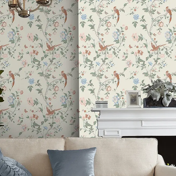 Laura Ashley Vliestapete Sommerpalast - Grün/Orange, Floral, 1.000 x 52 cm - Tapete mit zartem Muster aus Fasanen, Blumen und Ästen in Blau, Rosa und Grün auf hellem Grund, in einem Wohnzimmer gezeigt.