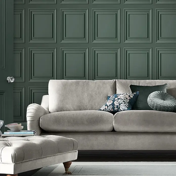 Laura Ashley Vliestapete Redbrook Holzplatte - Grün, Holzoptik, 1.000 x 52 cm - Helles graues Samtsofa und Ottoman mit Zierkissen.