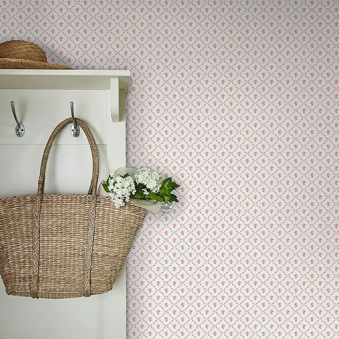 Laura Ashley Vliestapete Vliestapete Kate Gitterstruktur - Rosa, Floral, 10 x 0,52 m - Helle Tapete mit kleinem rosafarbenem Blumen- und grünem Blatt-Rautenmuster. Teilansicht mit Garderobe, Strohtasche, Strohhut.