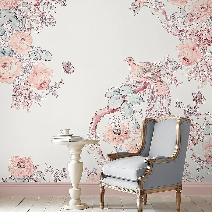 Laura Ashley Fototapete - Vlies - Elegante rosa-blaue Blumentapete mit Vogel- und Schmetterlingsmotiven, in einem Raum mit hellblauem Sessel.