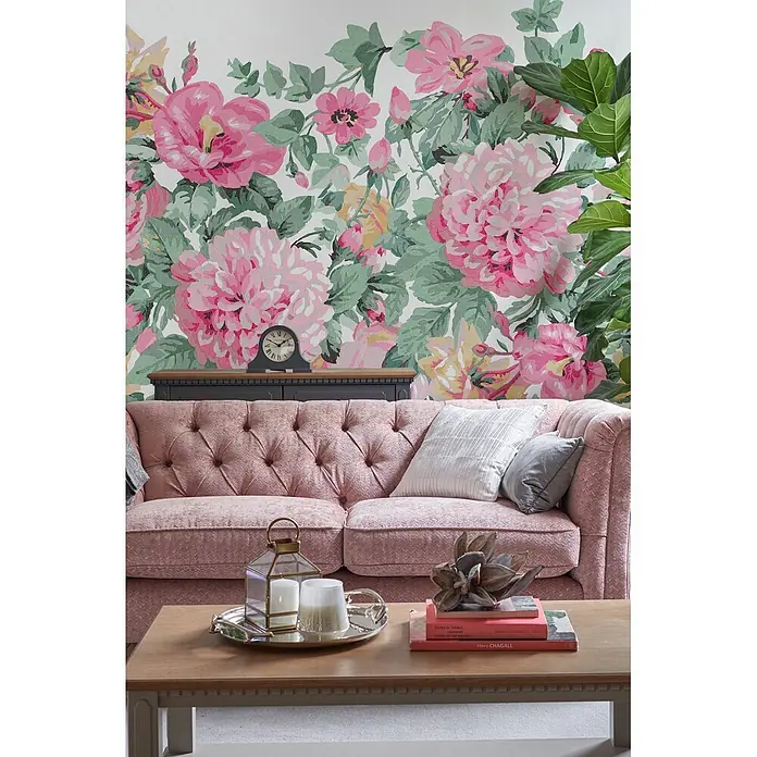 Laura Ashley Fototapete - Vlies - Rosafarbenes gestepptes Sofa in einem Wohnzimmer mit Kissen und floraler Tapete.