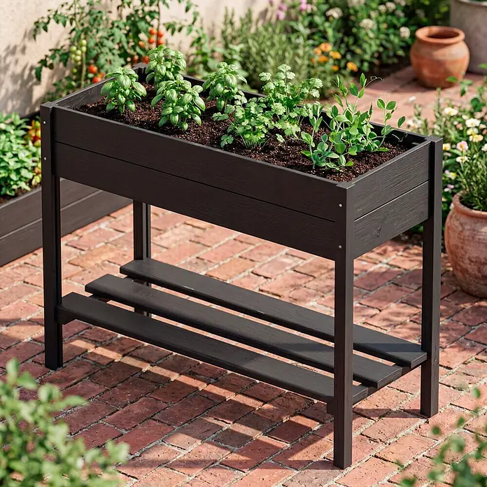 Plus Hochbeet - 88 x 37 x 79 cm, Mit Regalfach, Holz, Schwarz - Dunkles Hochbeet mit Ablage, bepflanzt mit Kräutern und Gemüse, auf einer Ziegelterrasse.