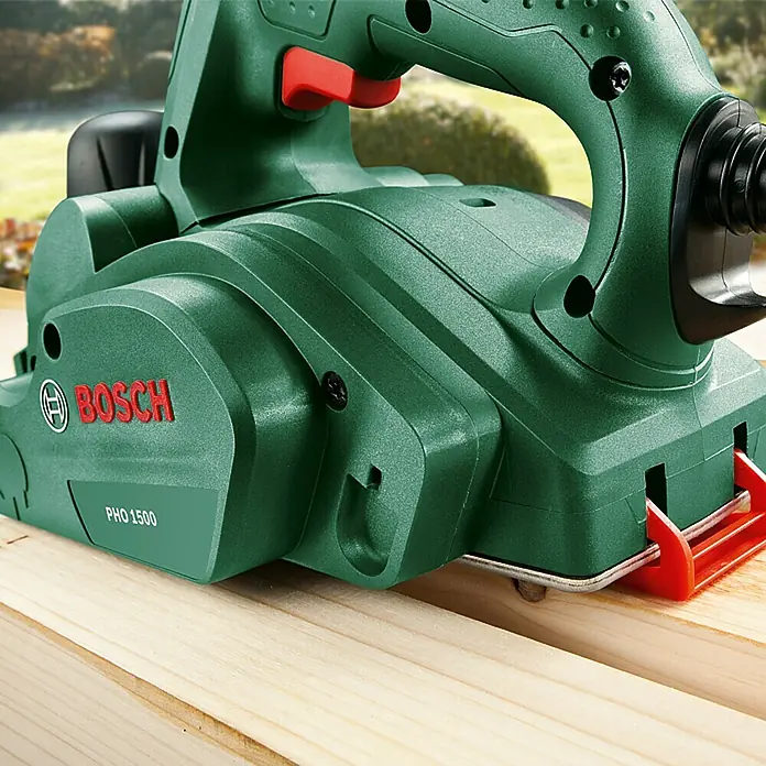 Bosch Handhobel PHO 1500 - 550 W, Hobeltiefe: 0 mm - 1,5 mm, 19.500 U/min - Grüne Bosch PHO 1500 Hobelmaschine beim Bearbeiten eines Holzstücks, ideal für Heimwerker und Profis.