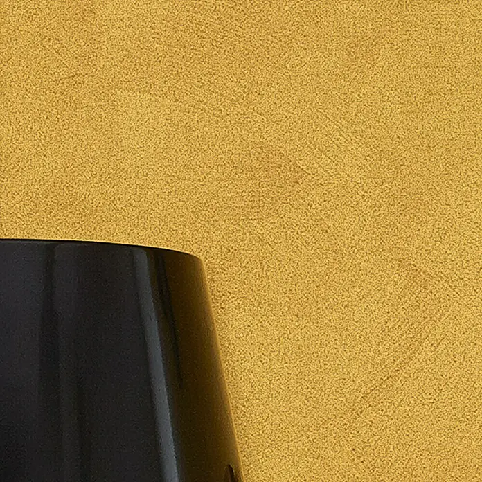 SCHÖNER WOHNEN-Farbe Trendstruktur Farbeffektputz Metall-Optik Effektfarbe - Mattgold, Matt, 2,5 l - Nahaufnahme einer eleganten, schwarzen Vase vor einem strukturierten, goldenen Hintergrund, ideal als Dekoration oder Blickfang.