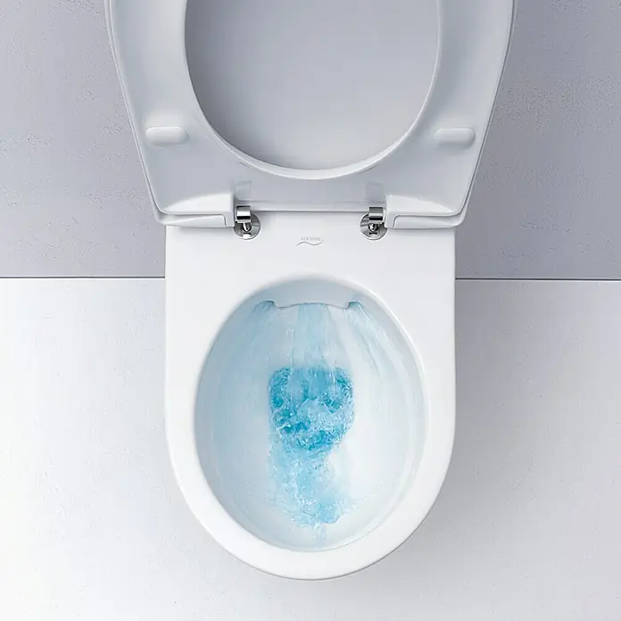 Geberit Renova Set WC suspendido - Sin borde de descarga, Salida WC: Horizontal, Con asiento de WC - Un inodoro suspendido blanco Keramag Renova No. 1 Plan con descarga de fondo y borde abierto, con agua azul dentro de la taza, descargando.
