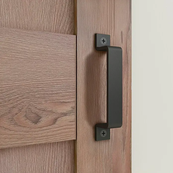 Inova Schiebetür-Komplettset Holzschiebetür Komplettset Eiche Doppelflügelig - 1.550 x 2.065 mm - Dunkelgrauer Metall-Griff an einer Holztür montiert.