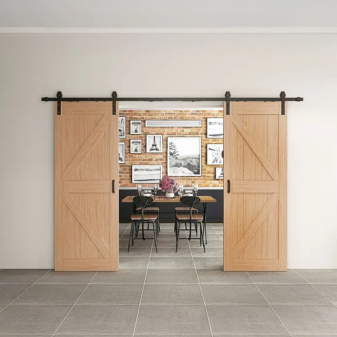 Inova Schiebetür-Komplettset Holzschiebetür Komplettset Eiche Doppelflügelig - 2.050 x 2.150 mm - Helle Holzschiebetüren mit schwarzer Hardware, teilweise geöffnet zu einem Esszimmer.