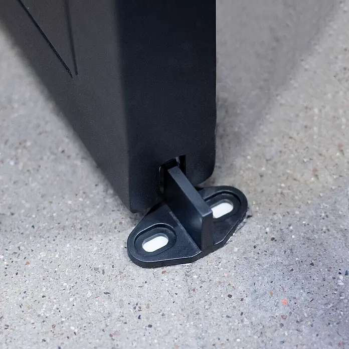 Inova Schiebetür-Komplettset Stahl Klarglas inkl. Softclose - 77,5 x 206,5 cm - Schwarze Kunststoff-Bodenführung für eine dunkle Platte, am Betonboden befestigt.