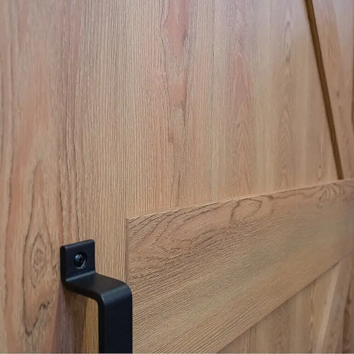Inova Schiebetür-Komplettset Holzschiebetür Eiche 1025 x 2150 Scheunentor mit Softlcose - 1.025 x 2.150 mm - Schwarzer Griff an einer hellen Holztür.