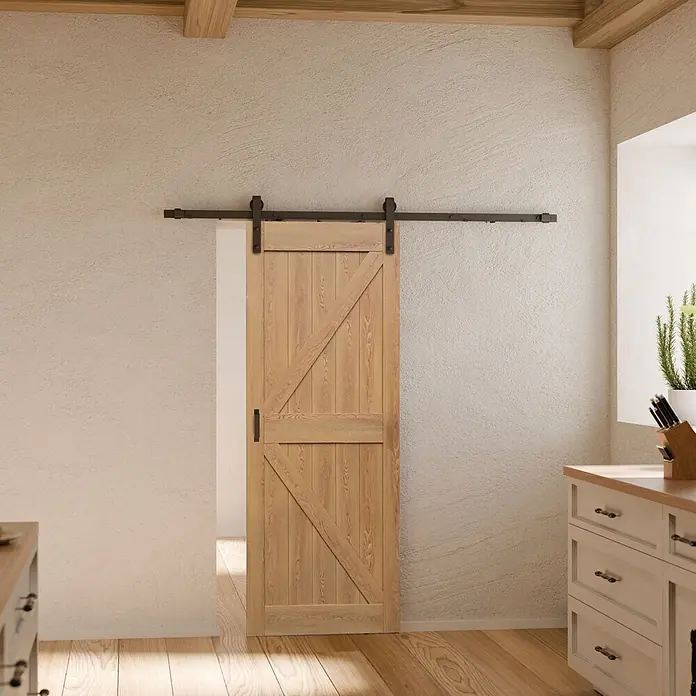 Inova Schiebetür-Komplettset Holzschiebetür Eiche 1025 x 2150 Scheunentor mit Softlcose - 1.025 x 2.150 mm - Helle Holz-Schiebetür mit schwarzer Beschläge, in einem Raum mit strukturierter Wand und Holzboden.