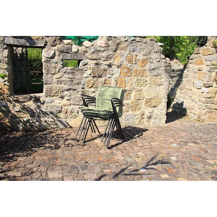 Acamp Stapelsessel Alpha Rope - Grün, 57 x 55 x 83 cm, 4 -tlg. - Gestapelte Outdoor-Stühle mit grünen geflochtenen Sitzen und schwarzen Metallgestellen vor einer rustikalen Steinmauer.