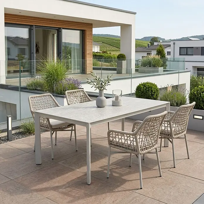 Acamp Gartenmöbel-Set Rom/Rom - 5 -tlg., Aluminium, TexRope, Grau,Beige - Ein modernes Outdoor-Essset mit hellgrauem Tisch und geflochtenen beigefarbenen Stühlen mit Kissen auf einer Terrasse.