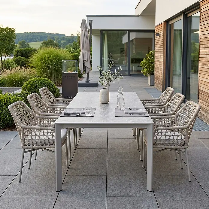 Acamp Gartenmöbel-Set Rom/Rom - 7 -tlg., Aluminium, TexRope, Grau, Beige - Moderner Outdoor-Esstisch in Hellgrau mit geflochtenen Seilstühlen auf einer Terrasse.
