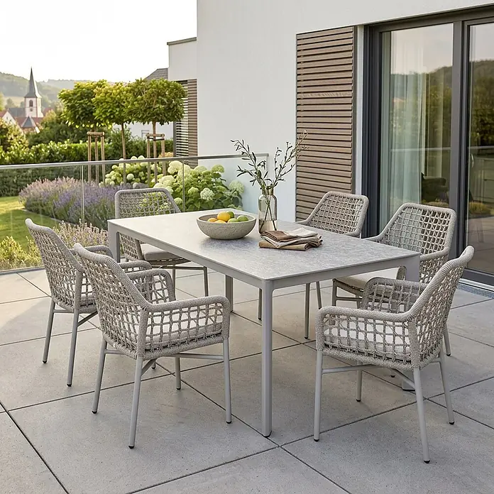 Acamp Gartenmöbel-Set Rom/Rom - 7 -tlg., Aluminium, TexRope, Grau, Beige - Moderne Outdoor-Essgruppe mit hellgrauem Tisch und sechs beigen Korbstühlen mit Kissen auf einer Terrasse.