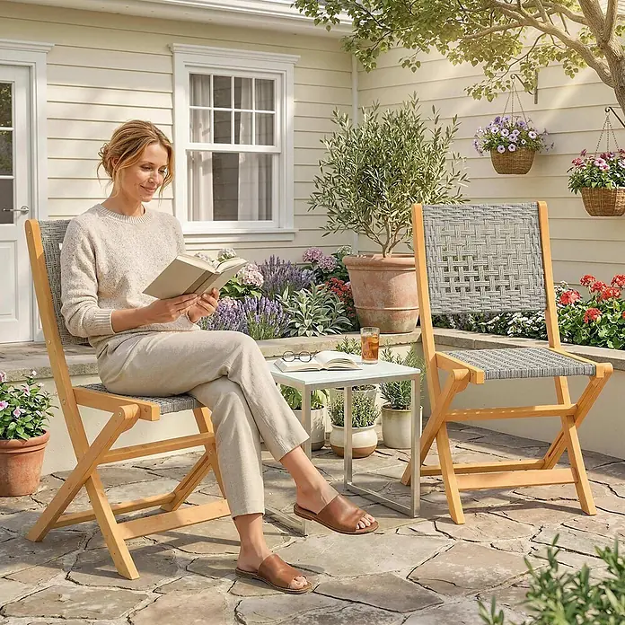Outsunny Gartenstuhl-Set - 2 Stk., Akazienholz, PE-Rattan, Klappbar, Grau, Braun - Zwei helle Holz- und graue geflochtene Gartenstühle, mit einer Frau, die entspannt ein Buch auf einer Terrasse liest.