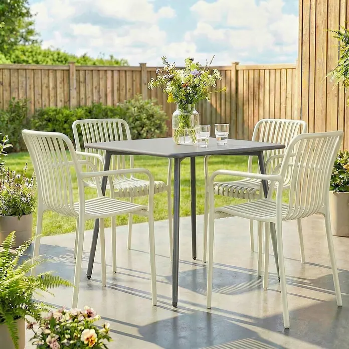 Outsunny Gartenstuhl-Set - 4 Stk., Kunststoff, Stapelbar, Cremeweiß - Eine Outdoor-Essgruppe mit grauem quadratischem Tisch und vier hellen Lattenstühlen auf einer Terrasse.