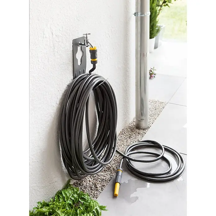Neptun Wand-Schlauchhalterung - Metall, Geeignet für: Handelsübliche Wasserhähne - Gartenschlauch auf einer Halterung an der Wand, bereit für die Gartenarbeit. Der Schlauch ist aufgerollt und mit einem gelben Anschlussstück versehen.