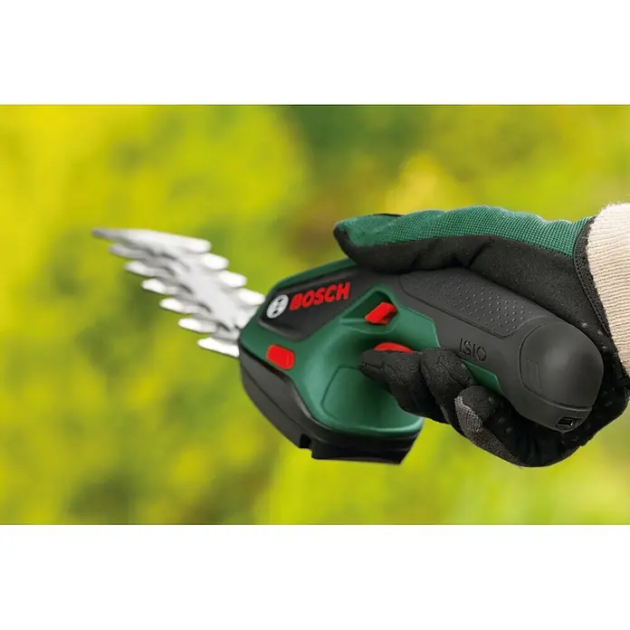 Bosch Akku-Gras- & Strauchschere ISIO 4 - 4 V, 1 Akku - Behandschuhte Hand hält grüne und schwarze Bosch ISIO Akku-Strauchschere mit roten Knöpfen und Metallklingen.