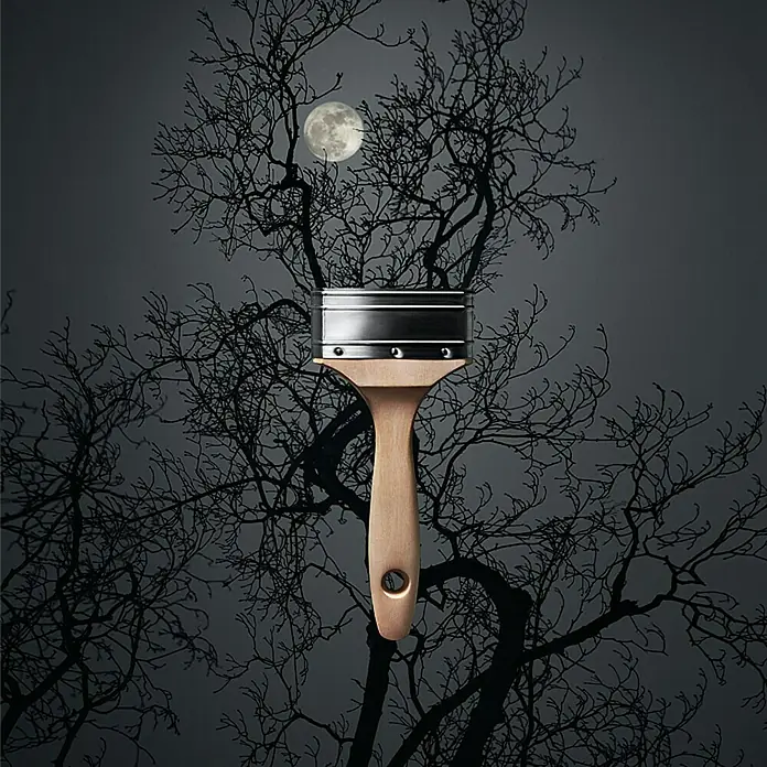 SCHÖNER WOHNEN-Farbe Wandfarbe Trendfarbe - Luna, Matt, 1 l, Konservierungsmittelfrei - Ein Pinsel vor einem dunklen Hintergrund mit einem Baum und einem Mond. Ein Werkzeug für kreative Gestaltung mit künstlerischem Flair.