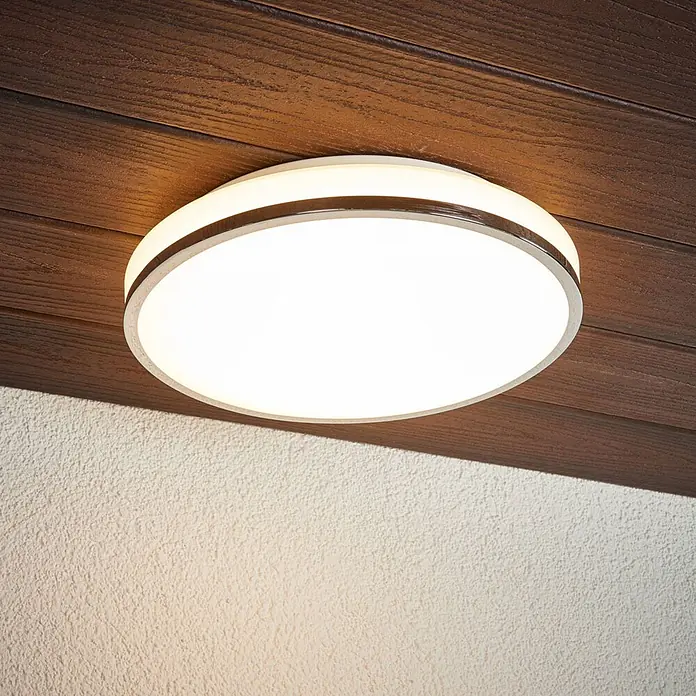 Lindby Deckenleuchte Lyss - weiß / opal - Runde LED-Deckenleuchte mit weißem Diffusor und Metallrahmen, an einer dunklen Holzdecke montiert.