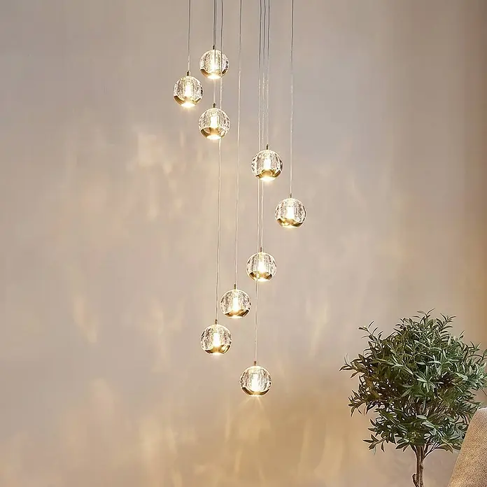 Lucande Pendelleuchte Hayley - klar / transparent, klar, gold - Kaskadierende Hängelampe mit mehreren klaren Kristallkugeln und goldfarbenen Akzenten, die ein warmes Licht abgeben.