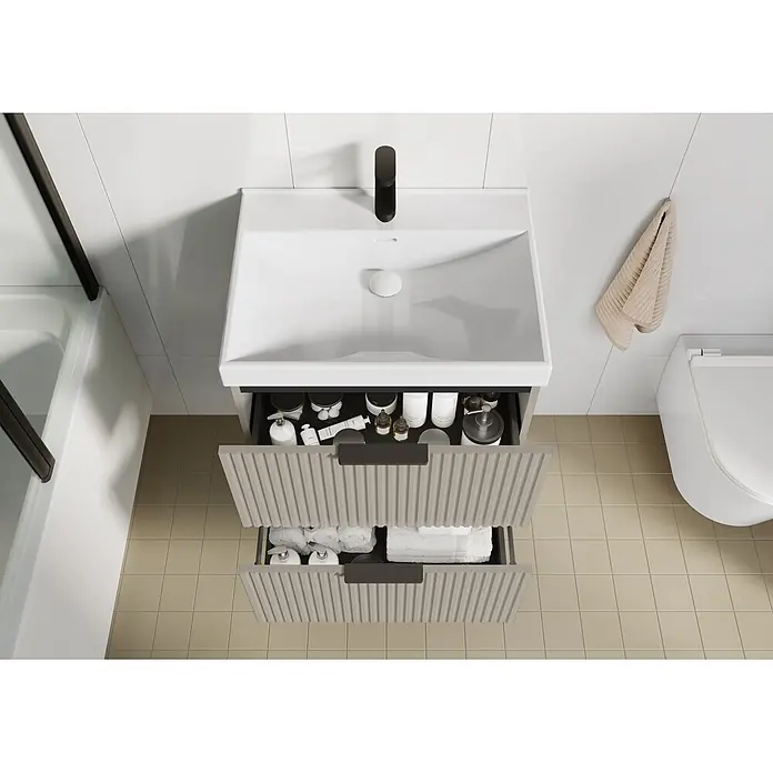 Riva Yasumi Waschtischunterschrank - B x T x H: 60 x 45,2 x 63,5 cm, Fume, Matt - Moderne Badezimmereinheit mit weißem Waschbecken, offene geriffelte graue Schubladen mit Toilettenartikeln und Handtüchern.