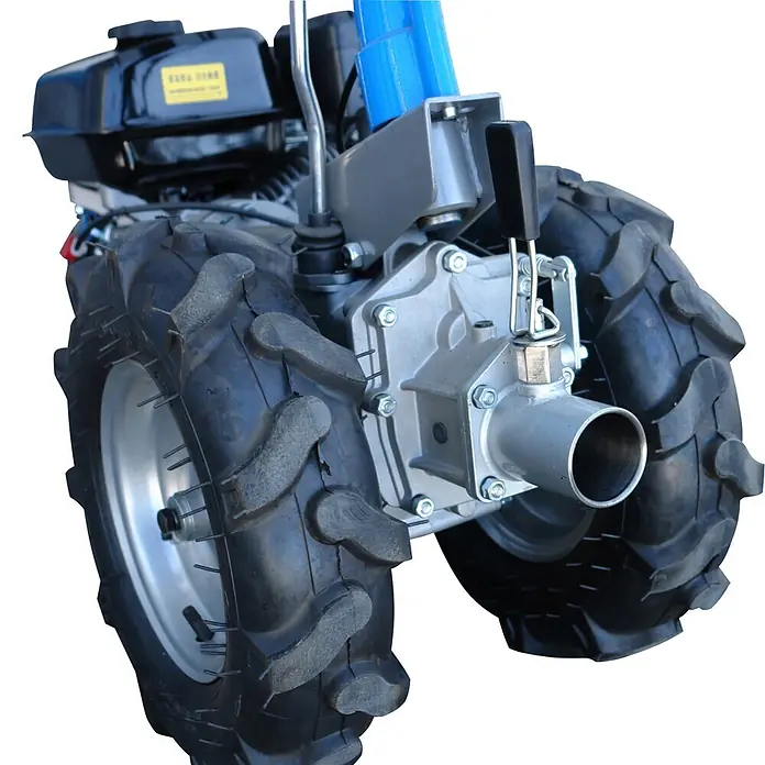 Güde Motoreinachser - Leistung: 4,8 kW, 4-Takt - Nahaufnahme des Antriebs einer Einachser-Fräse mit großen schwarzen Stollenreifen, silbernem Getriebe und schwarzem Kraftstofftank.