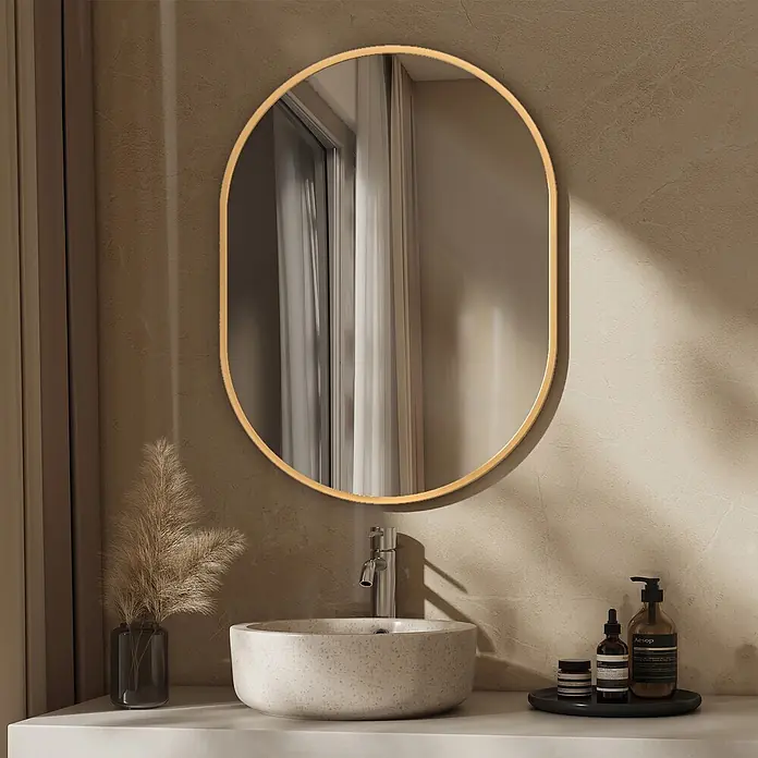 Emke Rahmenspiegel OM18 - Glas - Goldgerahmter Pillenspiegel über einem strukturierten Badezimmerwaschbecken mit Wasserhahn und Toilettenartikeln.