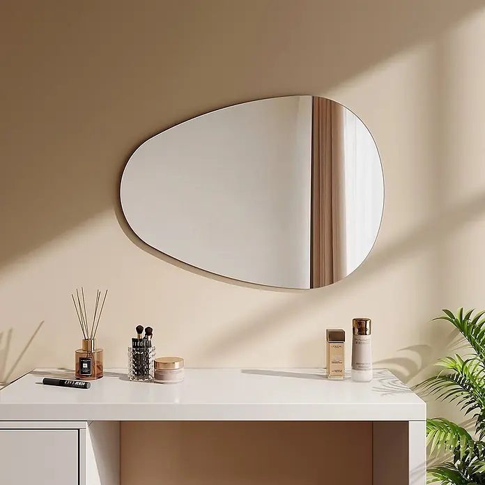 Emke Wandspiegel M33 -  - Unregelmäßig geformter Spiegel an einer hellen Wand über einem Schminktisch mit Kosmetika.