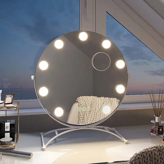 Emke Kosmetikspiegel CM11 - 40 x 47 cm, Rund, Weiß - Runder Schminkspiegel mit LED-Leuchten auf weißem Ständer, auf einem weißen Tisch am Fenster, der ein gemütliches Interieur spiegelt.