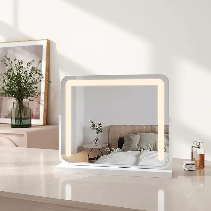 Emke Kosmetikspiegel CM08 - Rechteckig, Weiß - Weißer rechteckiger Schminkspiegel mit LED-Beleuchtung und Touch-Bedienelementen, der ein Schlafzimmer von einer Arbeitsplatte aus reflektiert.