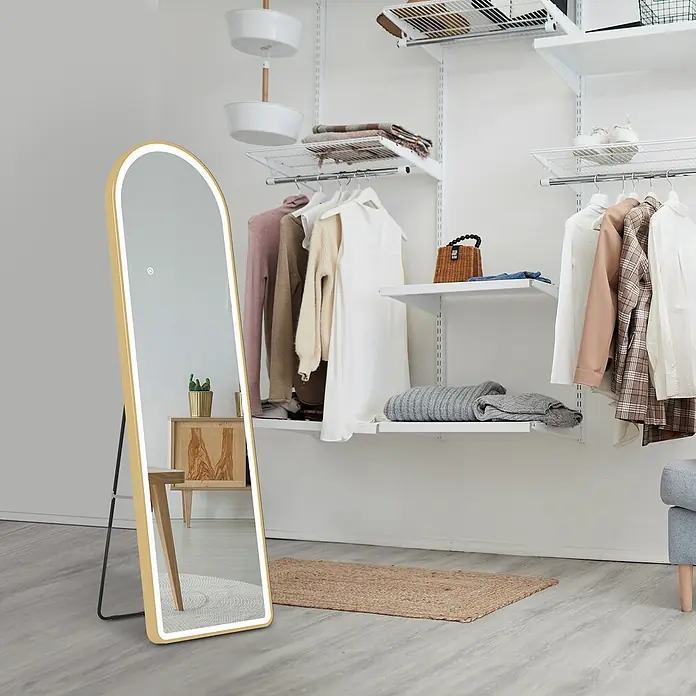 Emke Standspiegel FM06 - 45 x 147 cm, Glas - Goldgerahmter Bogen-Ganzkörperspiegel mit LED-Beleuchtung auf schwarzem Ständer, in modernem Kleiderschrank platziert.