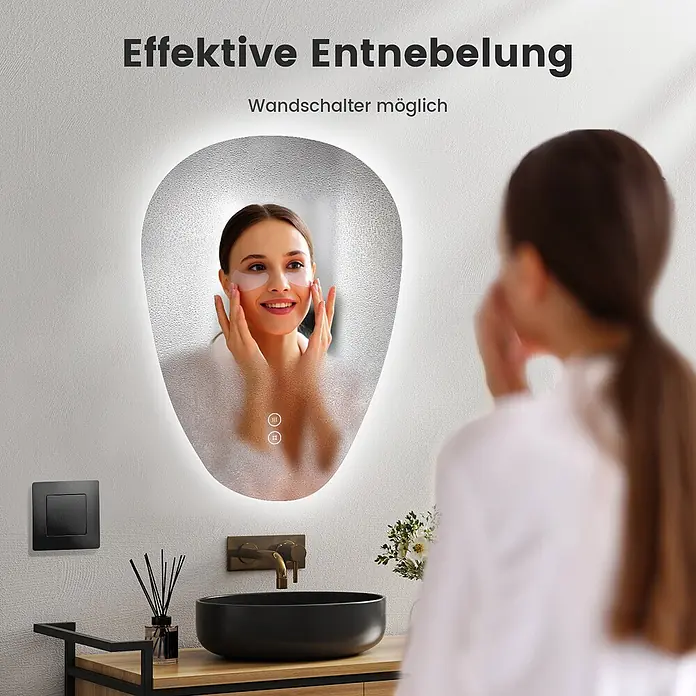 Emke Lichtspiegel Glowrim LM33 -  - Ovaler LED-Badezimmerspiegel mit Antibeschlagfunktion und Touch-Bedienung, der eine Frau beim Auftragen von Augenpads zeigt.