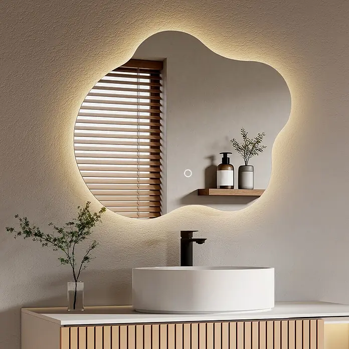 Emke Lichtspiegel Dimlite LM31 -  - Ein beleuchteter, organisch geformter Spiegel mit LED-Hintergrundbeleuchtung über einem weißen Waschbecken und schwarzem Wasserhahn in einem modernen Badezimmer.