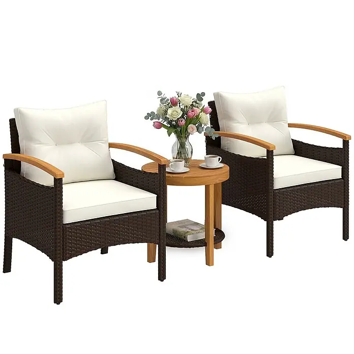 Outsunny Loungemöbel-Set - 3 -tlg., PE-Rattan, Stahl, Polyester, Akazienholz, Schaumstoff, PP-Baumwolle, inkl. Kissen, Braun, Cremeweiß, Naturholz - Braunes Rattan-Gartenmöbelset mit zwei Stühlen, weißen Kissen, Holzarmlehnen und einem runden Holztisch mit Blumen und Kaffee.