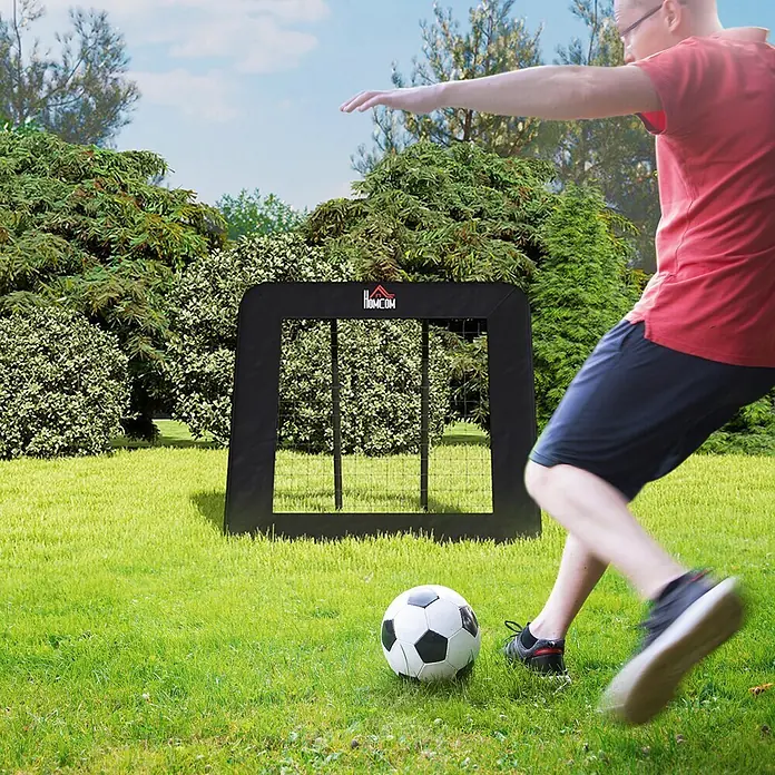 Homcom Sportnetz Rebounder - Metall, Schwarz - Eine Person schießt einen Ball auf ein schwarzes HomCom Fußballtor auf einem Rasenfeld.