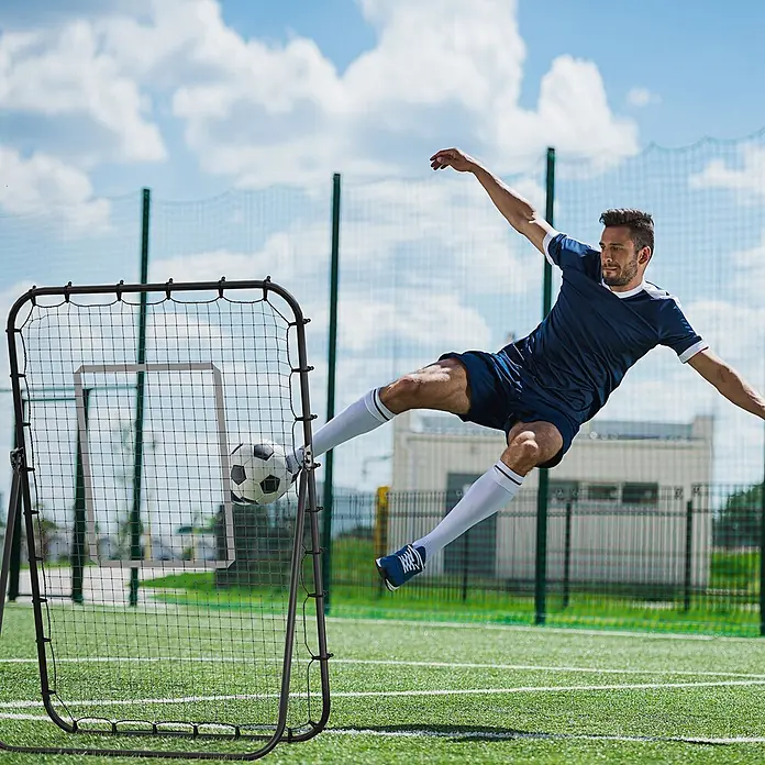 Homcom Sportnetz Rebounder - Metall, Schwarz - Schwarzes Fußball-Rebounder-Netz in Gebrauch, ein Spieler schießt einen Ball hinein.
