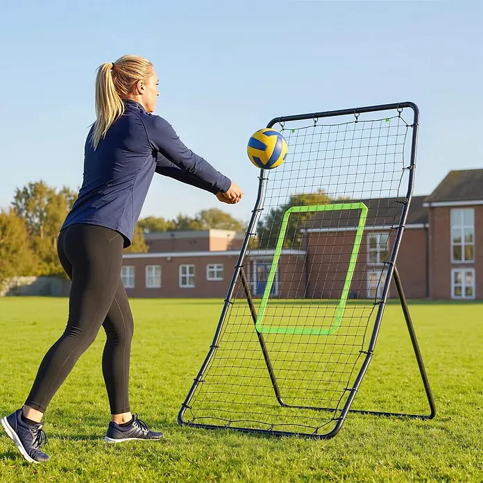 Homcom Sportnetz Rebounder - Stahl, Schwarz - Frau übt Volleyball mit einem schwarzen Rebounder-Netz mit grünem Ziel und einem gelb-blauen Volleyball.