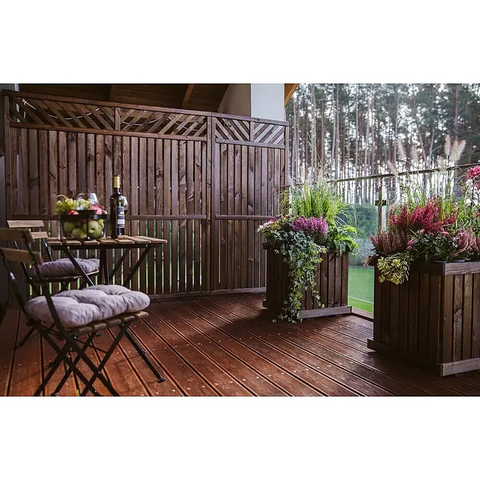 Werth Holz Sichtschutzelement Victoria - B x H: 179 x 179 cm, Holz, Braun - Gemütliche dunkelbraune Holzterrasse mit kleinem Tisch, Stühlen und Pflanzgefäßen, mit Waldblick.
