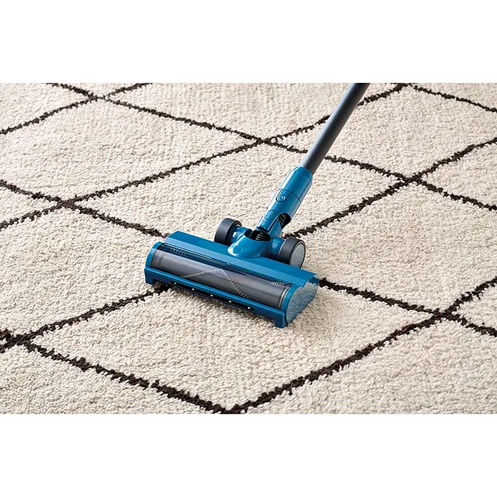 Nilfisk Aspirador de batería Move - 150 W, Volumen de recipiente: 0,2 l, Negro, Con soporte de pared - Cabezal azul de aspiradora de escoba con cepillo giratorio limpiando una alfombra blanca estampada.