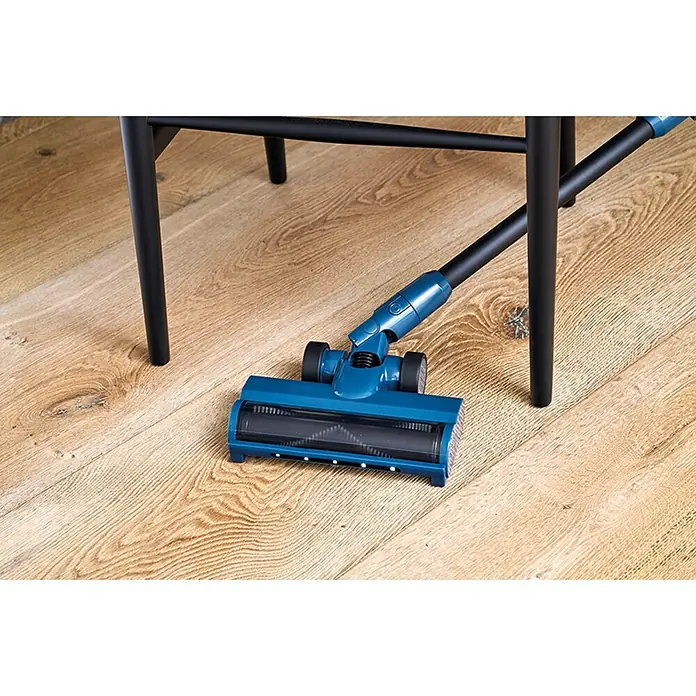 Nilfisk Aspirador de batería Move - 150 W, Volumen de recipiente: 0,2 l, Negro, Con soporte de pared - Cabezal de aspiradora azul con rodillo negro limpiando bajo muebles negros en suelo de madera.