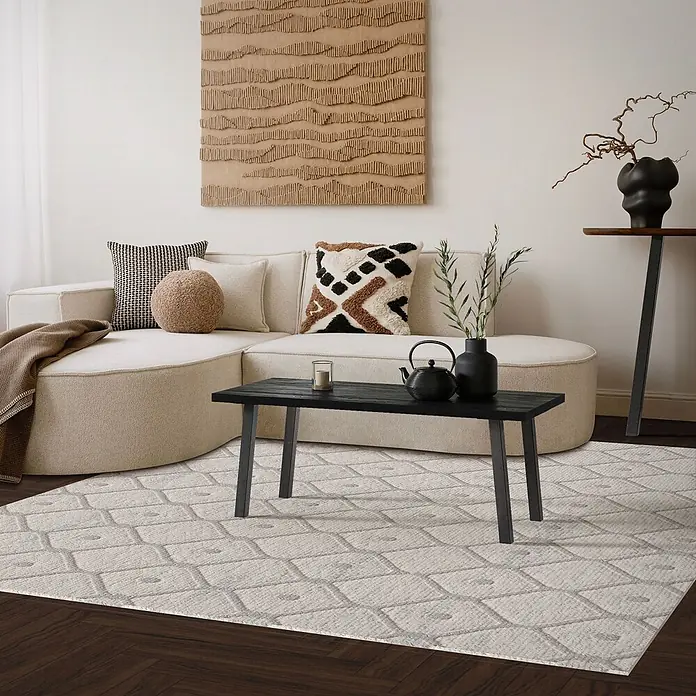ML-Design Tischgestell 4er Set Tischkufen schräg Möbelfüße und aus Stahl I-Form - Traglast: 500 kg, Stahl - Ein heller Teppich mit subtilem geometrischem Muster liegt auf dunklem Holzboden, teilweise unter einem beigen Sofa und schwarzem Couchtisch.