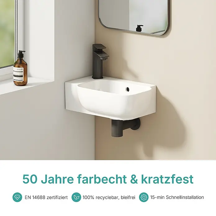 Emke Waschbecken Ceraform CB23 - B x L: 21 x 40 cm, Hahnloch: Links, Mit Überlauf, Weiß - Weißes wandmontiertes Waschbecken mit dunkelgrauem Wasserhahn und Abflussrohr, in einer modernen Badezimmerecke.