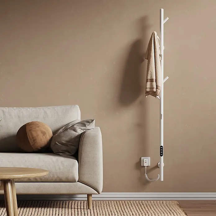 Emke Elektro-Badheizkörper Orbrad PHR -  - Weißer vertikaler Heizstab mit Digitalanzeige, an eine Steckdose angeschlossen, mit Handtuch, neben einem Sofa.