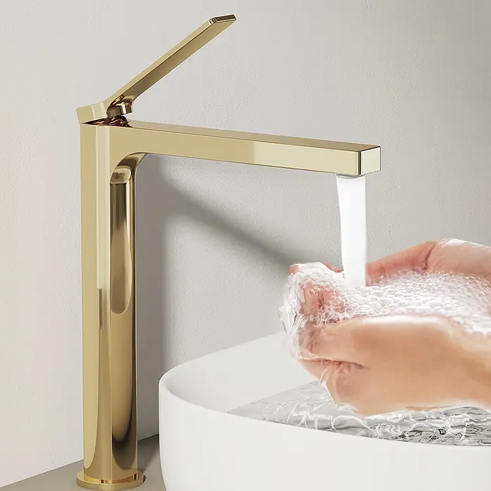 Emke Waschtischarmatur Arcspout XF21 - Gold, Glänzend - Goldfarbener Wasserhahn gießt Wasser in ein weißes Waschbecken, während Hände gewaschen werden.