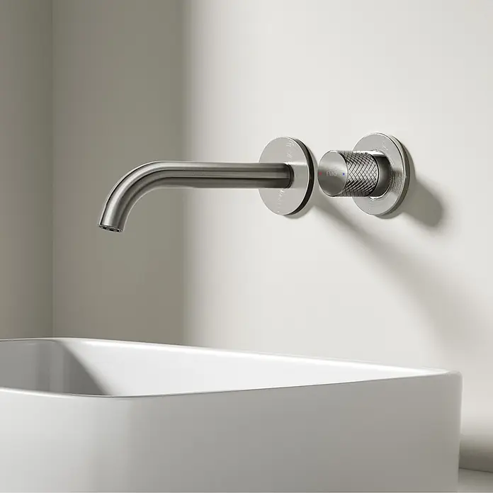 Emke Waschtischarmatur Griprill XF22 - Grau, Glänzend - Wandmontierte Armatur aus gebürstetem Metall mit gerändeltem Griff, EMKE-Logo und Temperaturanzeigen, über einem weißen Waschbecken.