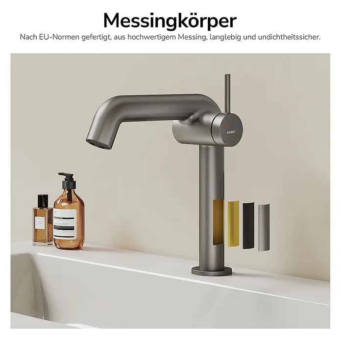Emke Waschtischarmatur Flowcurv XF24 - Grau, Matt - Dunkelgraue Messing-Waschtischarmatur auf einem weißen Waschbecken, mit verschiedenen Oberflächenmustern daneben.